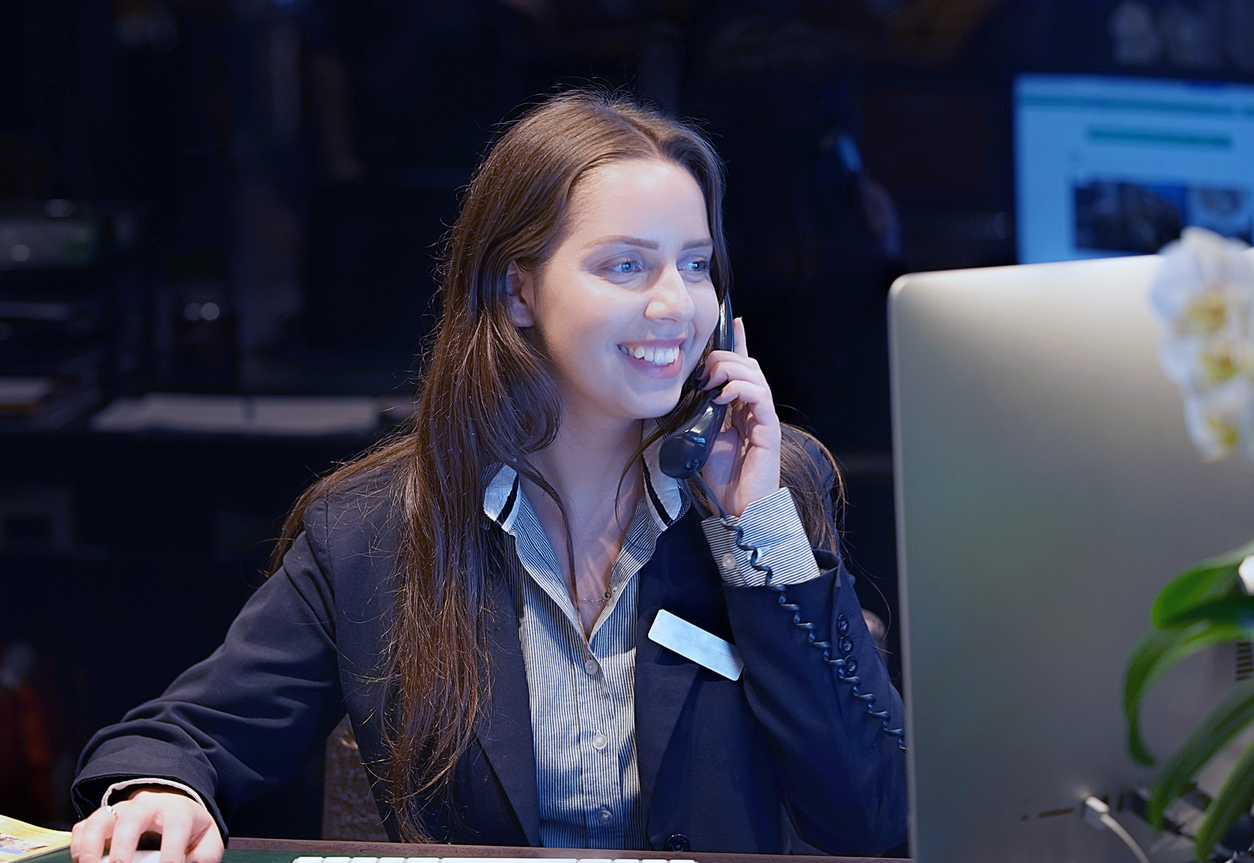 A woman smiling while on the phone at her desk 