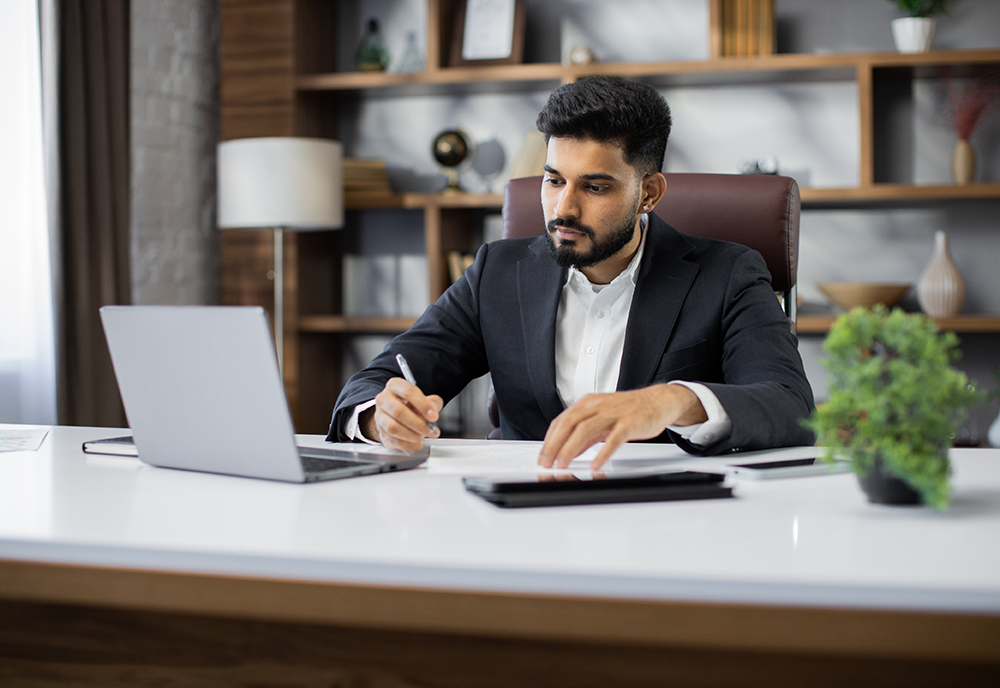 business man sits at computer writing something down