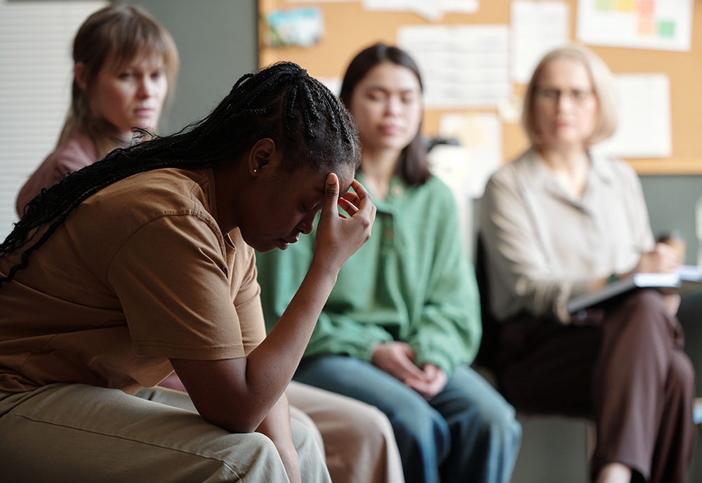 a women holds her head in her hands during a group meeting