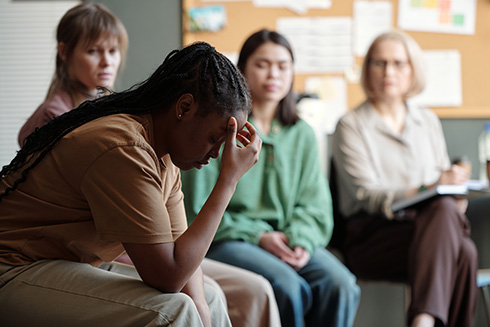 a women holds her head in her hands during a group meeting