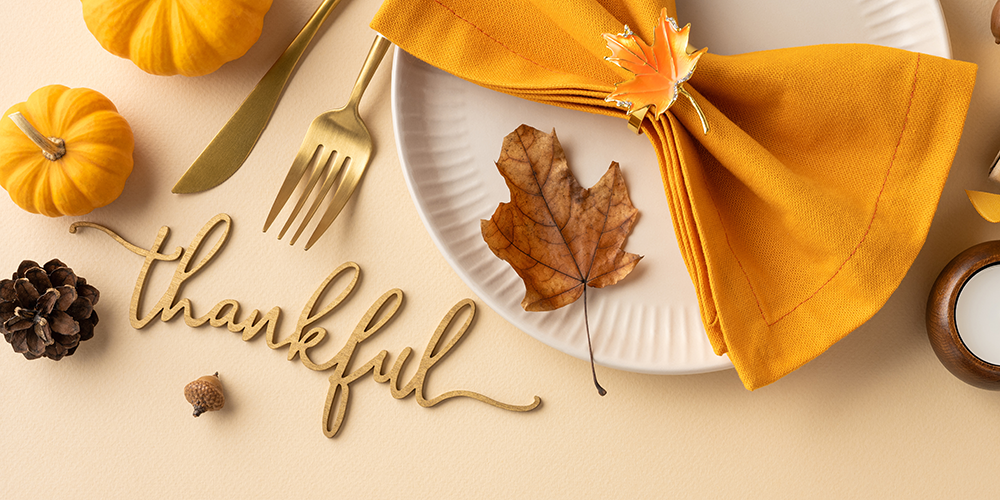 a plate setting on a table with the words thankful written in script