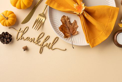 a plate setting on a table with the words thankful written in script