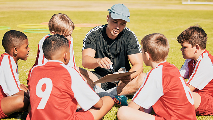 Coach sitting with young athletes in a circle