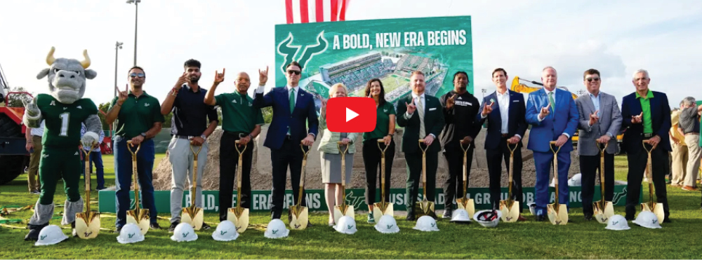 Group of people with shovels and hardhats standing where the new stadium will be built. Link goes to USF News page.