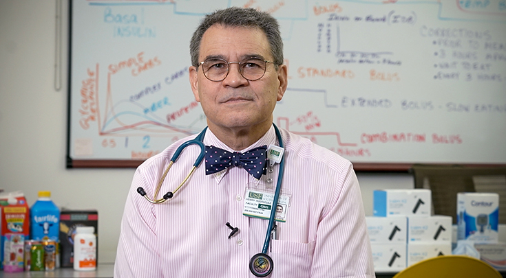 Dr. Rodriguez is sitting in a large classroom wearing a bowtie.