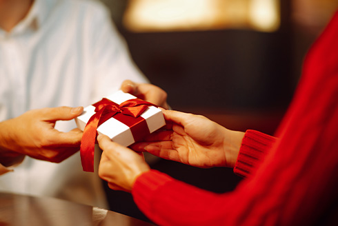 A person in red exchanging a wrapped gift