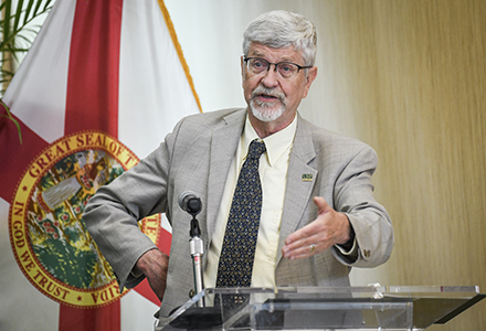 Sten Vermund, MD, PhD, speaks at a lecturn with a Florida flag behind him.