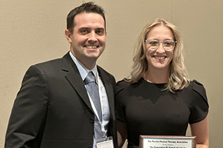 A man and a woman in a room holding an award.