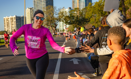 Students high-fiving runners in the half marathon