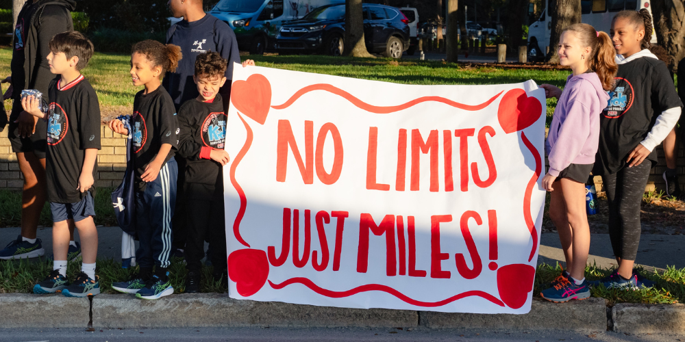 Students holding a sign reading, "No limits, just miles"