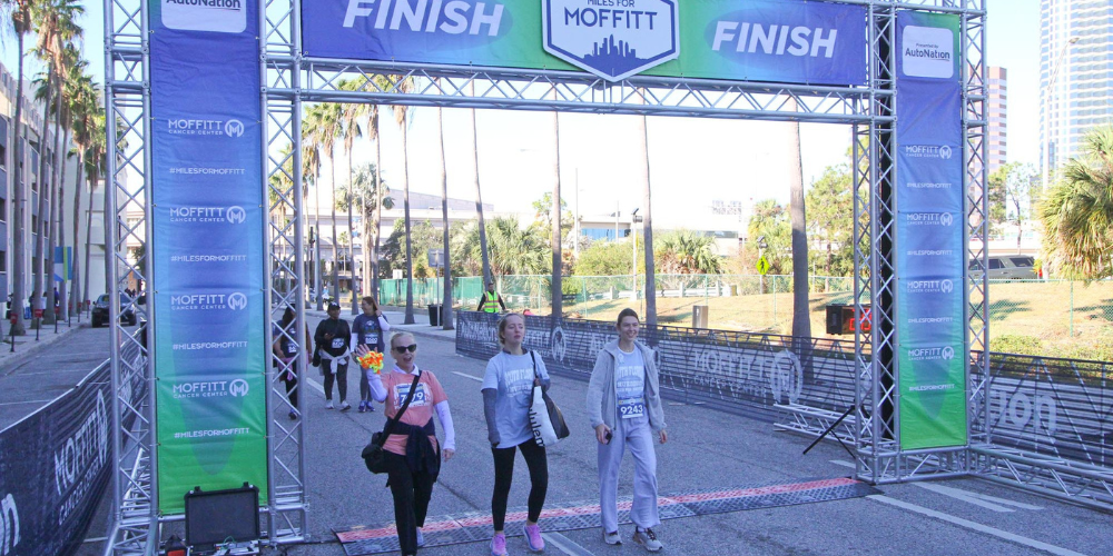 Emily Morris walks across the finish line during the Miles for Moffitt 5k