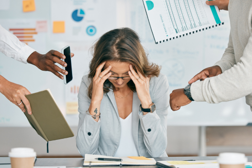 a person with her head in her hands at their work desk