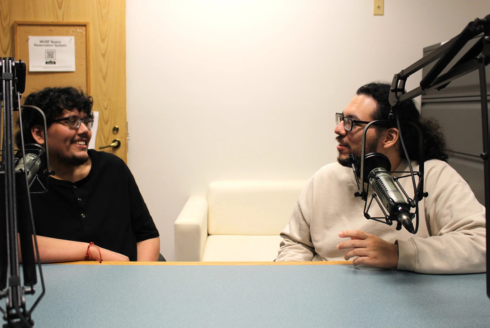 two men speaking with mics in a recording studio