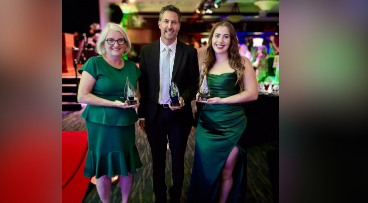 three people holding awards