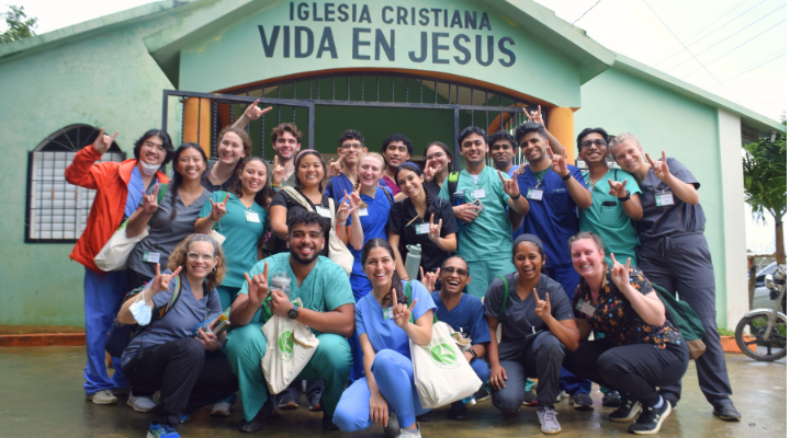 Students on the Dominican Republic trip sport their scrubs while smiling in front of a church