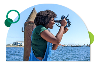 Student by the ocean looks into a telescope device