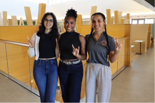 Serena Bhaskar, Karla Evangelista De La Rosa, and Arelis Rodriguez Martinez make Go Bulls signs while posing in the Judy Genshaft Honors College