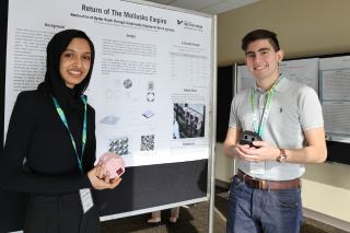 USF Judy Genhaft Honors College students Amreen Naveen and Tzuriel Garcia stand in front of a research poster tittled: "Return of the Mollusks Empire"