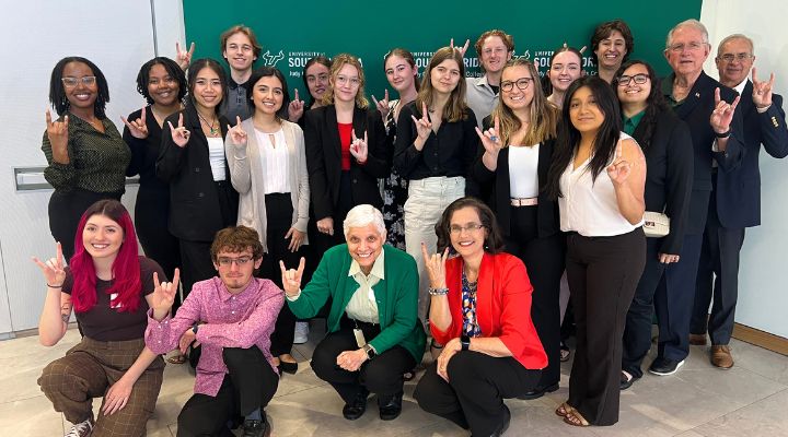 A group of Jenkins scholars and Publix charities pose together at a Jenkins brunch, everyone making a Go Bulls hand sign.