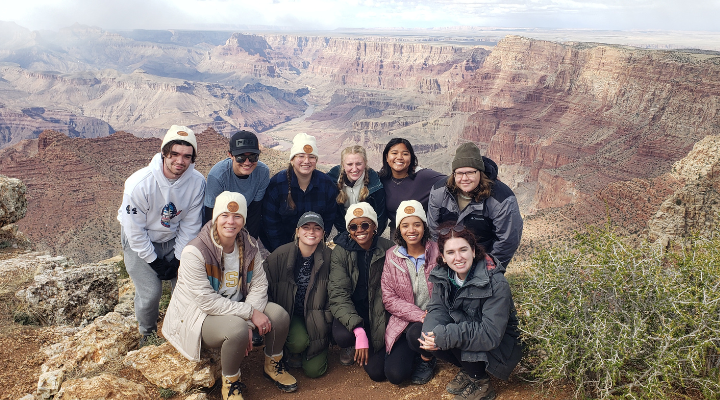 Sutdents tour a national park and stand on a peak. 