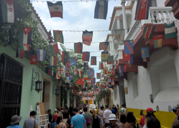 Flags from around the world hang over a busy, pedestrian filled street in Colombia
