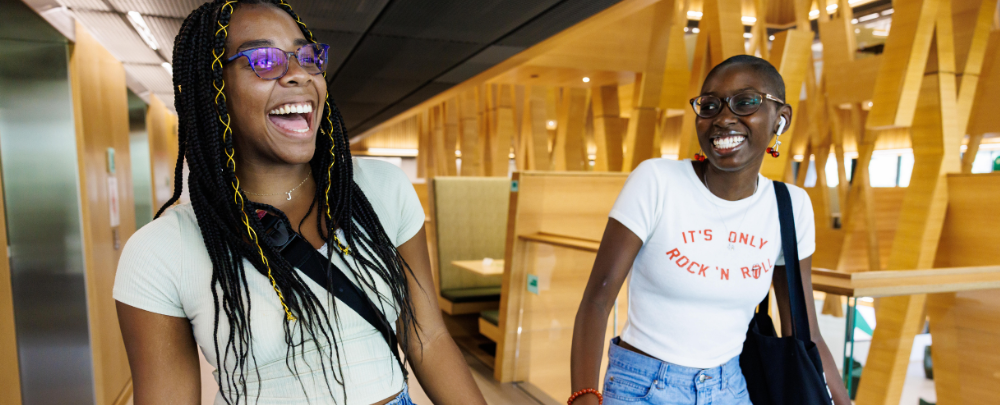 Two students smile while walking the halls of the Honors college