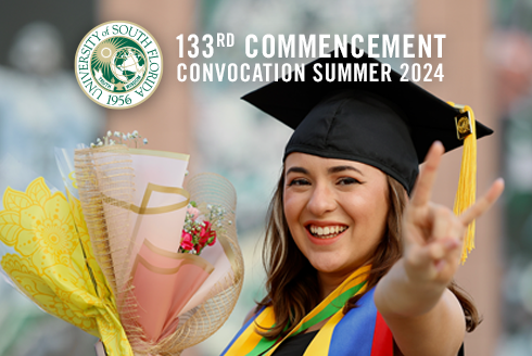 Honors Graduate smiles in their cap and gown while holding flowers.