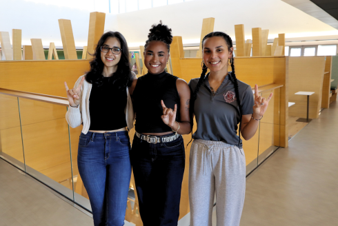 Serena Bhaskar, Karla Evangelista De La Rosa, and Arelis Rodriguez Martinez make Go Bulls signs while posing in the Judy Genshaft Honors College