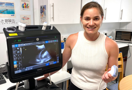Casey Farrell smiles while holding lung ultrasound machinery