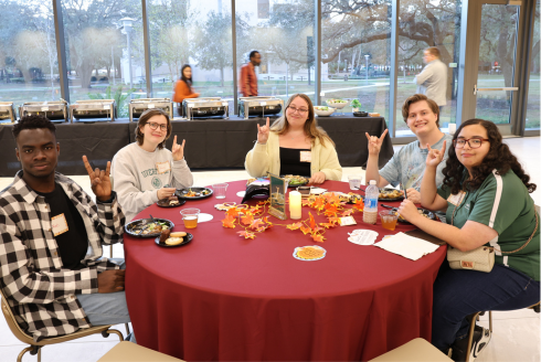 Students smile around a table at the Judy Genshaft Honors College Friendsgiving event.