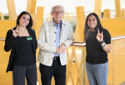 Hnery McLeish holds up the Go-Bulls sign with Honors students Fabiana and Reva