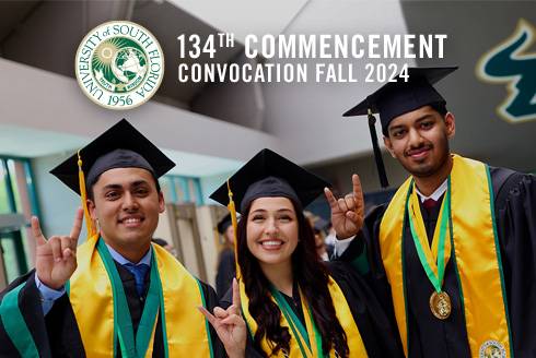 Graduation students smile in their cap and gowns. 