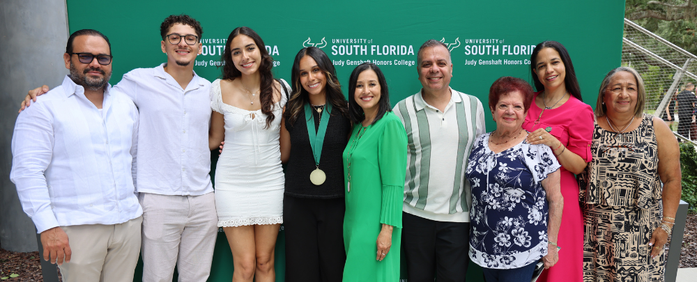 Honors grad smiles with family after commencement ceremony.