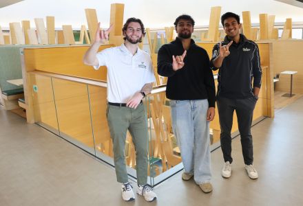 Parker Olive, Aakash Vijeesh, and Rahul Jain pose with the "Go Bulls" hand sign on the fifth floor of the Honors building.