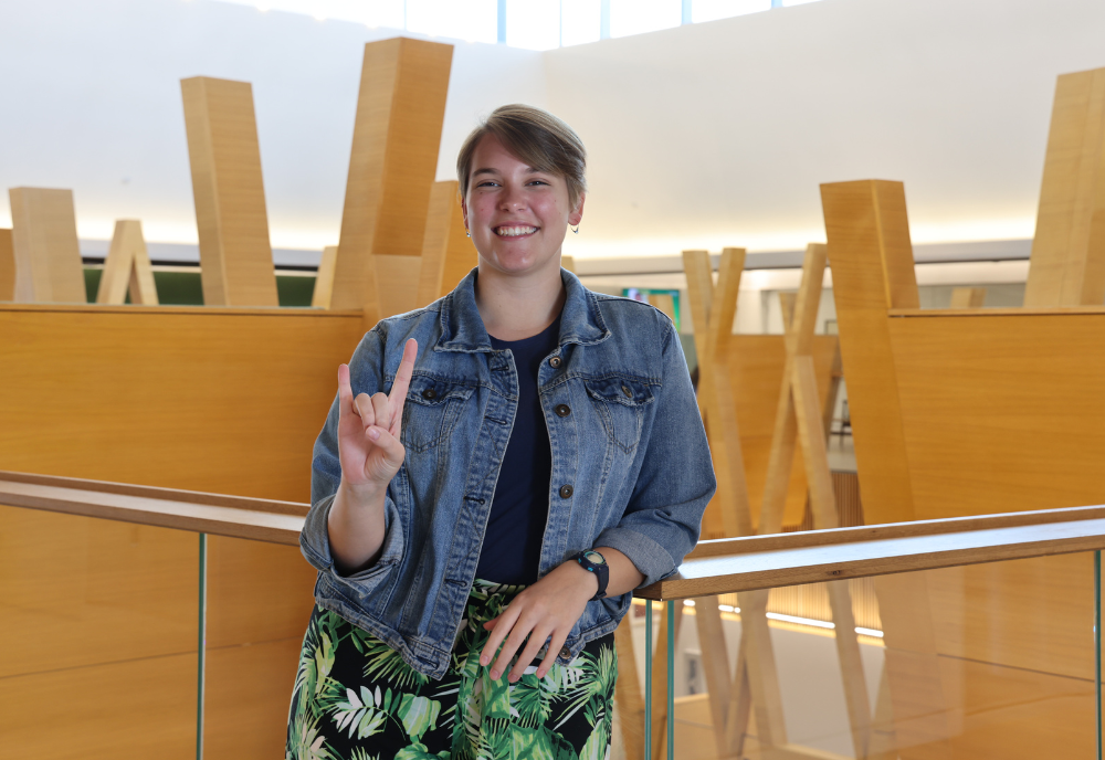 USF St. Petersburg Judy Genshaft Honors College alum Gabby Schwager poses while making a Go Bulls hand sign.