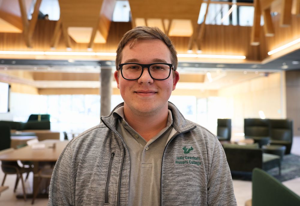 Mykyta Nechaiev, smiling on the first floor of the Honors Atrium