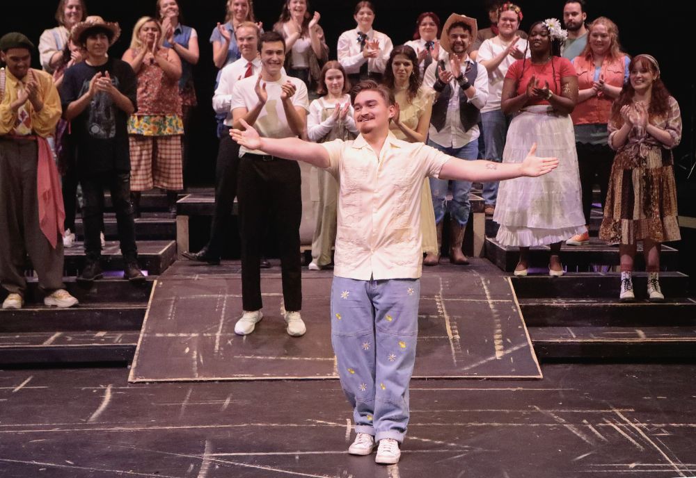 Preston Kifer welcomes applause on stage after one of his shows, with his fellow cast members clapping behind him. 