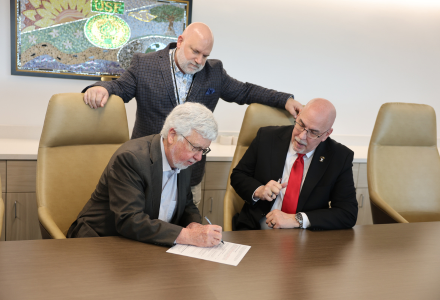 Judy Genshaft Honors College Dean Charles Adams signs an agreement with associates from Veterans Affairs Health Care in a conference room.