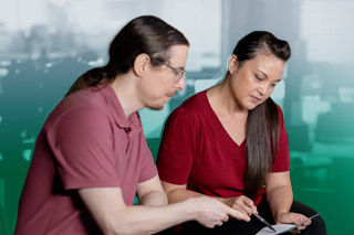 a man and a woman sit pointing at a paper