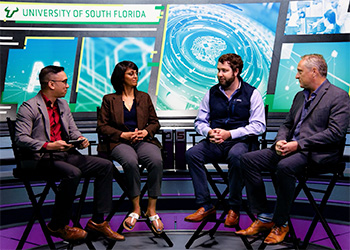 a panel of professors sit at a round table discussing a topic