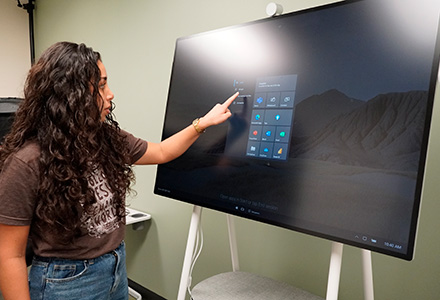 girl stands at smart board pointing