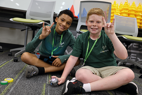 Two students hold up a USF U during everyone can code camp