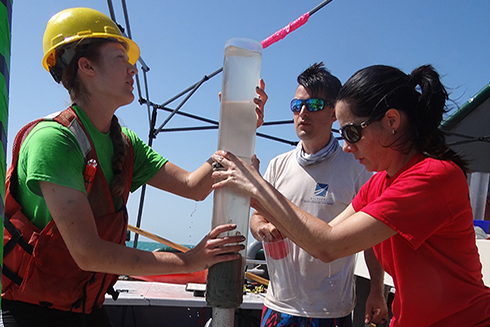 Dr. Patrick Schwing (background) and Dr. Isabel Romero (foreground, right) assist with a sediment core taken in the wake of Deepwater Horizon. Photo Credit: C-IMAGE