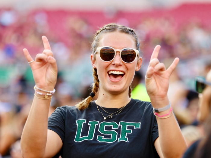 Student smiling and doing a Go Bulls hand gesture.