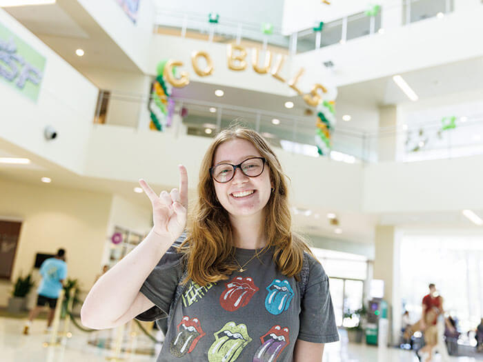 Student smiling and doing a Go Bulls hand gesture.