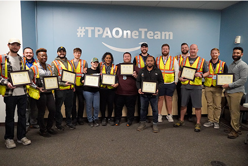 a large group from amazon poses with their certificates