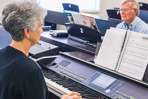 Two older adults play the piano