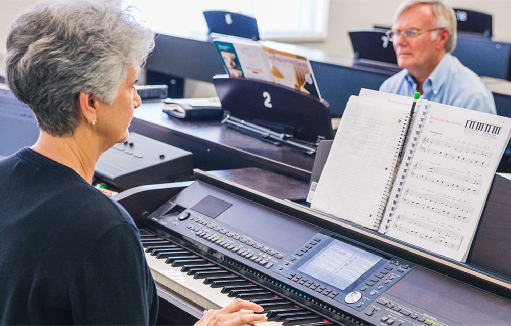 Two older adults play the piano