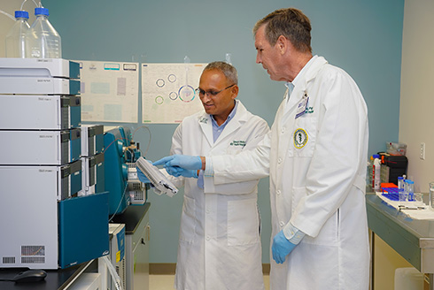 Dr. Yeatman and Halade looking at samples in their lab together