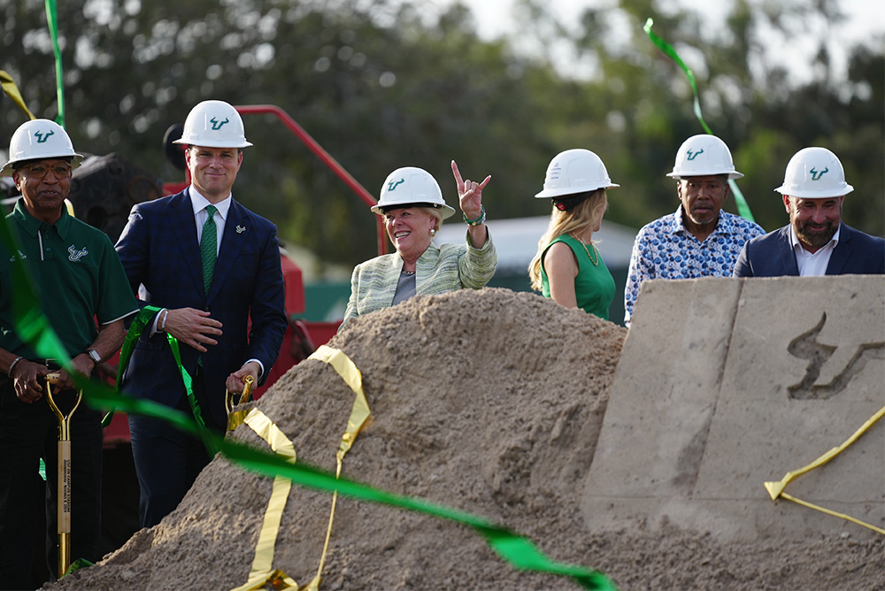 President Rhea Law and other campus leaders pose in front of the new on-campus stadium groundbreaking site